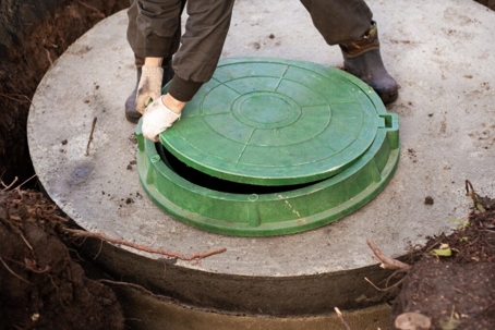 A person opens a septic tank for professional septic services.