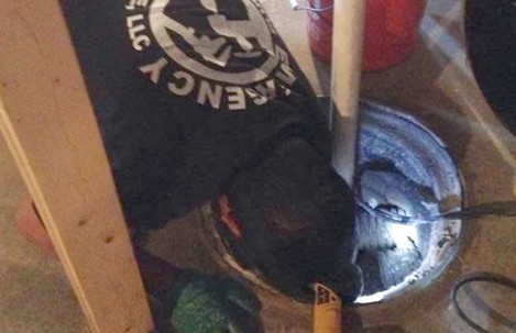 A man in a uniform peers into a dark sump pit