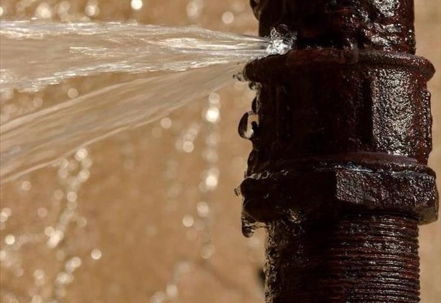 Close-up of a rusted, leaking water pipe