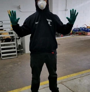 A person wearing a mask and gloves stands in a storage area