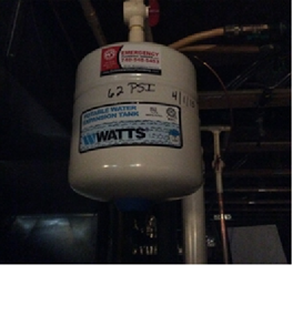 A white water pressure tank manufactured by Watts is shown indoors