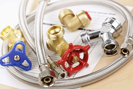 There are brass fittings, flexible hoses, and valves with red and blue handles.