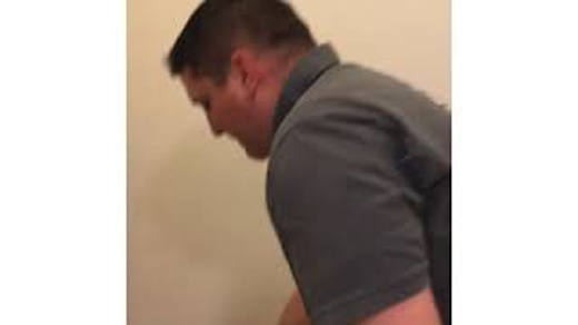 Man in a gray shirt looks down.