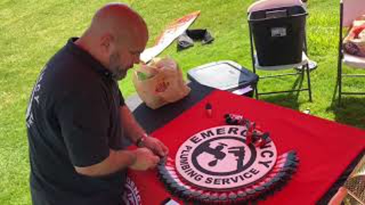 A man is putting together an Emergency Plumbing Service promotional sign.