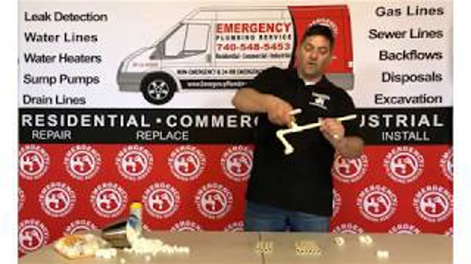 A man holds a pipe and fittings against a backdrop with emergency plumbing service information.