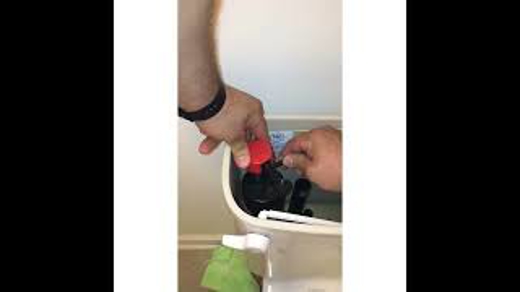This image shows hands adjusting the inner workings of a toilet tank, likely as part of a repair.
