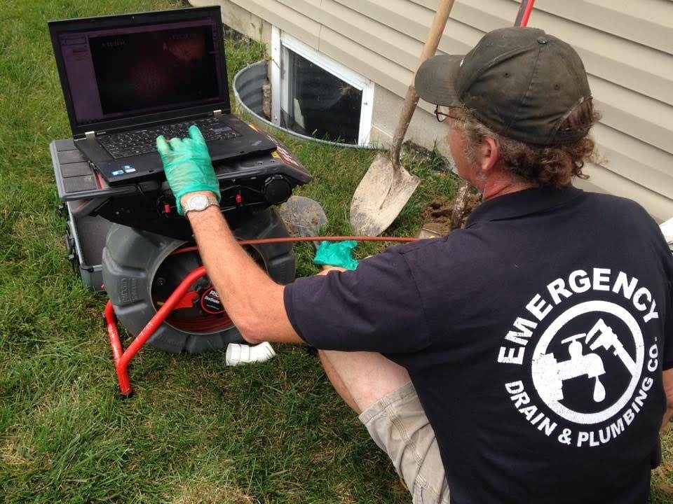 A technician inspects drain pipes with a camera and laptop, diagnosing plumbing issues.
