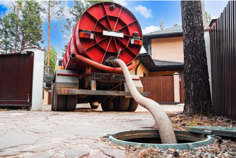 A red septic truck pumps out a septic tank.