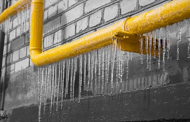 Holiday Plumbing Tips 14 A horizontal yellow gas pipe with icicles runs along a brick wall