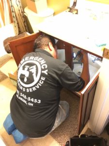 What To Expect When Expecting Us 2 A plumber kneels to repair the plumbing under a bathroom sink.