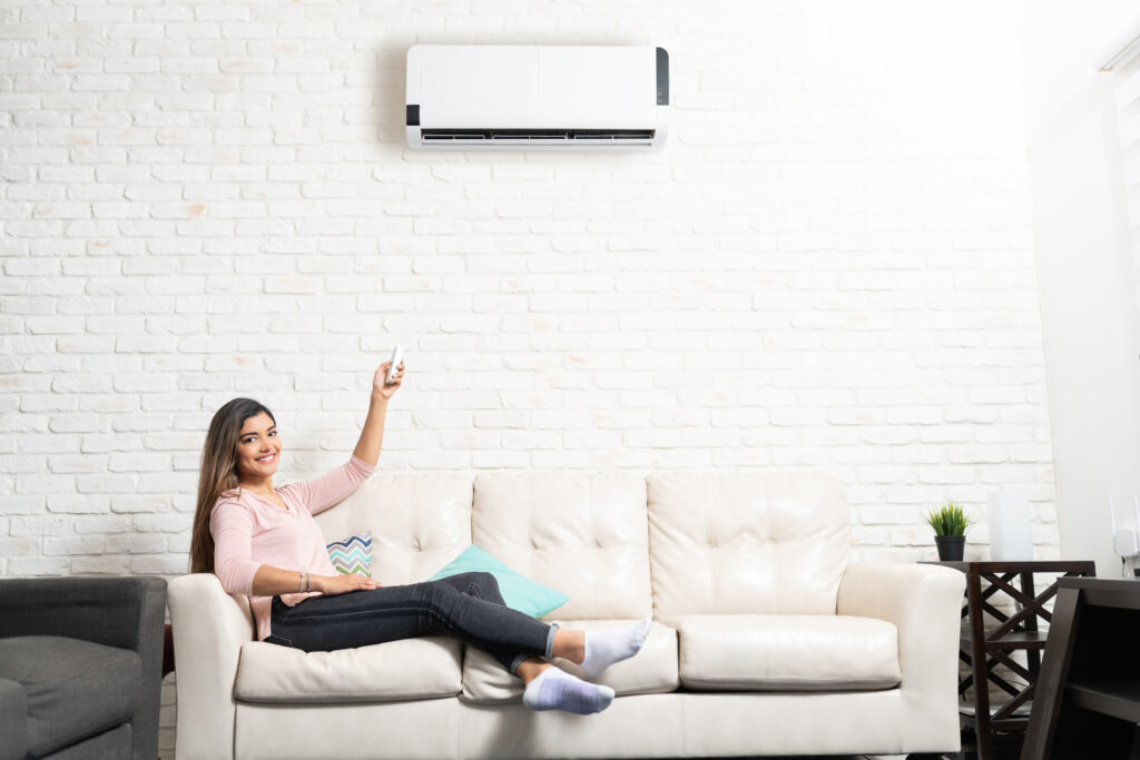 Smiling Woman Is Adjusting Temperature Of Air Conditioner